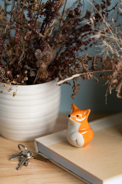 Small fox figurine on a book with dried plants in the background