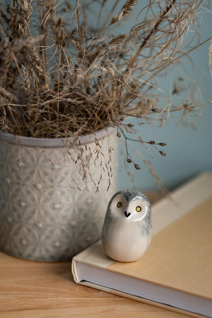 Decorative owl figurine on a book with a potted plant in the background